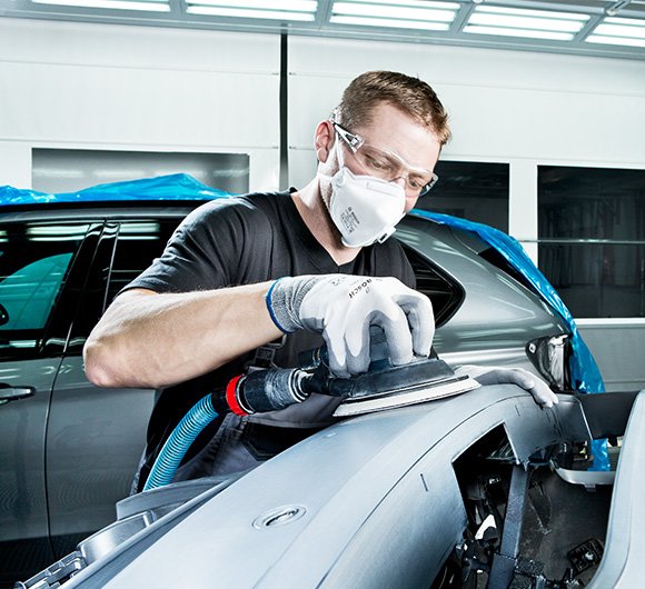 Man sanding a car in a workshop