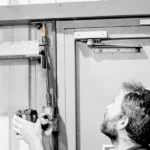 Man working on a door mechanism with tools.