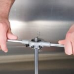 Hands using a tool to manipulate a metal object