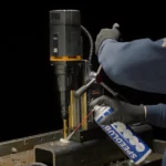 Person lubricating a drilling machine with spray