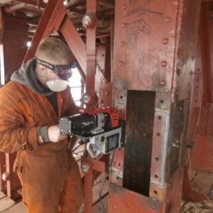 Worker using a power tool on steel structure