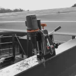 Magnetic drill on construction beam outdoors.