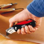 Hand using a Bessey utility knife on leather.