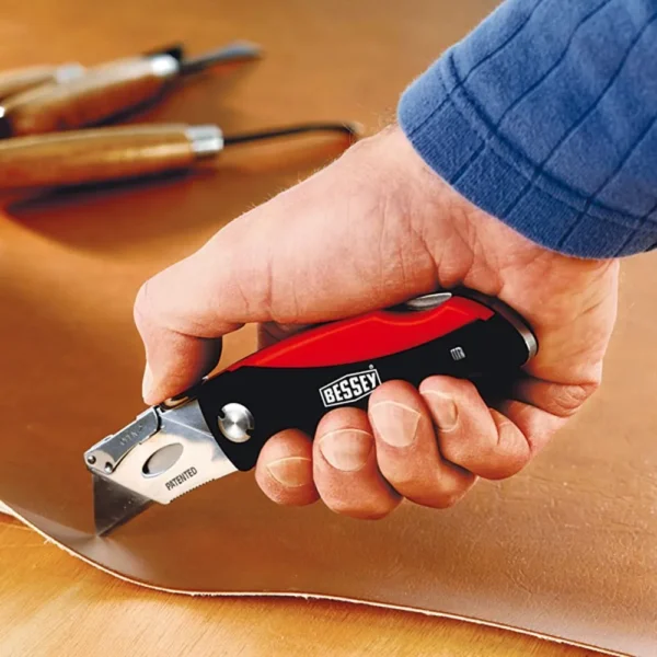Hand using a Bessey utility knife on leather.