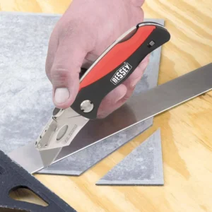 Person cutting metal sheet with a utility knife.