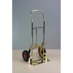 Metal hand truck with red wheels, on a table.