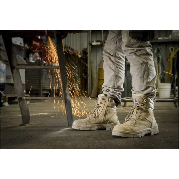 Worn work boots in a workshop, sparks flying.