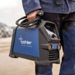 Person holding a Böhler welding machine outdoors.