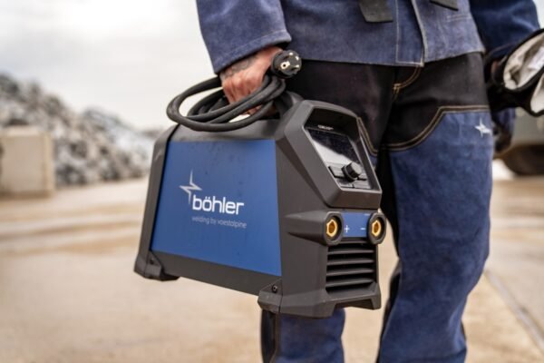 Person holding a Böhler welding machine outdoors.